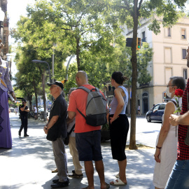 Un home espera amb una rosa per entrar a la capella ardent de Núria Feliu i observa la geganta de l'artista, a les portes del districte de Sants-Montjuïc, a Barcelona.