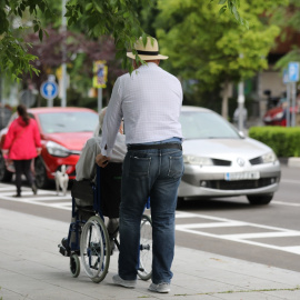 Un hombre pasea a una persona de edad avanzada en silla de ruedas. Imagen de Archivo.