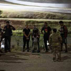 Los migrantes son detenidos por tropas de la Patrulla Fronteriza y la Guardia Nacional de EE. UU. en Eagle Pass, Texas, cerca de la frontera con México, el 30 de junio de 2022.