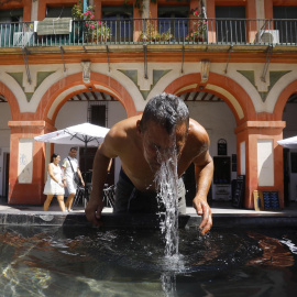 Un hombre se refresca en la fuente de la plaza de la Corredera de Córdoba