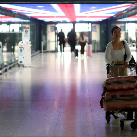 Una pasajera traslada su equipaje en un carrito en la Terminal 5 del aeropuerto londinense de Heathrow . REUTERS/Hannah McKay