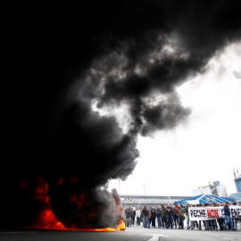 Trabajadores de la planta Alcoa de A Coruña, durante la concentración que llevan a cabo a las puertas de la fábrica, donde han quemado neumáticos y cortado el tráfico, en protesta y en lucha contra el cierre de la aluminera, que supondría el despido