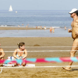 (9/09/06) Una pareja toma el sol mientras un hombre participa en la carrera nudista "Patxi Ros" de Sopelana (Euskadi), a 9 de septiembre de 2006.