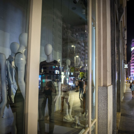 29/08/2022. Varias personas pasan por una tienda de ropa con las luces apagadas, a 10 de agosto de 2022, en Madrid