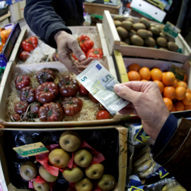 Un cliente paga con un billete de 5 euros en un puesto de fruta de un mercado en Niza (Francia). REUTERS/Eric Gaillard