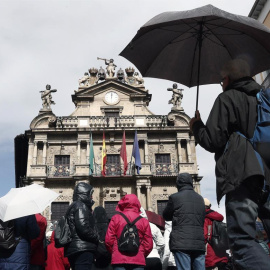 Un grupo de turistas se protegen con sus paraguas de la lluvia junto al Ayuntamiento de Pamplona, uno de los lugares preferidos para la Semana Santa. EFE