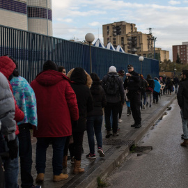 Un agente de policía reparte los turnos de los 80 solicitantes de asilo que serán atendidos en la comisaría de Aluche.- JAIRO VARGAS