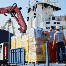 Operarios de Open Arms supervisan la carga de ayuda humanitaria al buque tras recibir la autorización para zarpar del puerto de Barcelona./ Alejandro García (EFE)