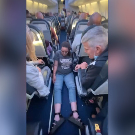 Una mujer se arrastra por el suelo de un avión