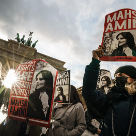 28/09/2022-Manifestantes sostienen pancartas con una imagen de Mahsa Amini durante una concentración en reacción a su muerte, frente a la Puerta de Brandenburgo en Berlín, Alemania, 28 de septiembre de 2022.