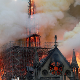 El humo ondea cerca de los andamios cuando el fuego envuelve la aguja de la catedral de Notre Dame. / Reuters