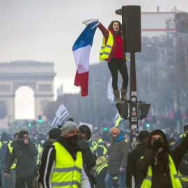 Una mujer grita consignas subida a un semáforo durante una protesta en los Campos Elíseos en París (Francia) hoy, 24 de noviembre de 2018. El ministro francés del Interior, Christophe Castaner, culpó hoy a la ultraderecha y a su líder, Marine Le Pen