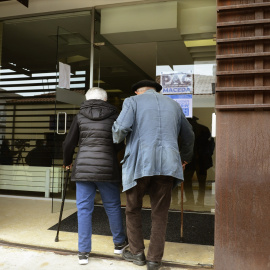 Dos personas mayores entran por la puerta de la residencia.