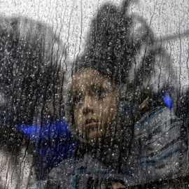 Una niña centroamericana que viaja en una caravana de migrantes, toma un autobús fuera de un refugio temporal en el este de Tijuana, México, el 6 de diciembre de 2018 | Guillermo Arias/AFP