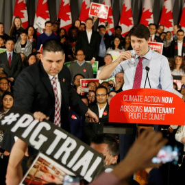 Justin Trudeau observa cómo un miembro de su equipo de seguridad reduce a un asistente durante un reciente mitin en Toronto. (REUTERS)