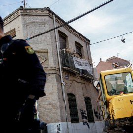 Un agente de Policía Nacional frente a una máquina retroexcavadora durante la demolición del edificio okupado ‘La Higuera’, en el barrio de Tetuán, a 14 de octubre de 2022, en Madrid (España).