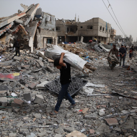 Un hombre transporta objetos recogidos entre los escombros en el campo de refugiados de Nuseirat, en el centro de la Franja de Gaza, a 18 de abril de 2024.