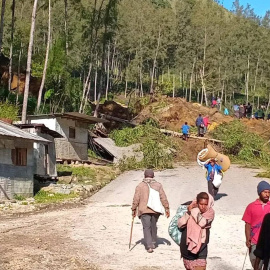 Varias personas caminan con sus pertenencias tras el desprendimiento de tierra en Kaokalam, en Papúa Nueva Guinea.