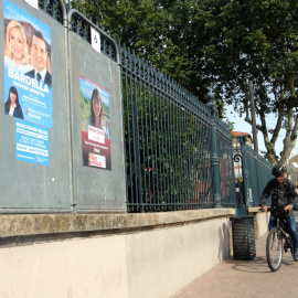 Dos cartells, un de Reagrupament Nacional i del Nou Front Popular amb un ciclista de fons a Perpinyà