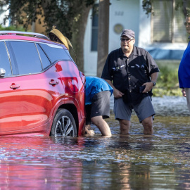 Varias personas intentan mover un automóvil averiado en una calle inundada tras la llegada del huracán Milton a tierra en Clearwater, Florida, EE.UU., el 10 de octubre de 2024.