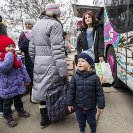 Mujeres y niños que huyen de Ucrania se preparan para tomar un autobús a Alemania, cerca de un centro de clasificación de refugiados en un estadio deportivo en Chisinau, Moldavia.