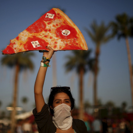 La pizza, alimento de los festivales en el Coachella. Una mujer posa con una réplica gigante.