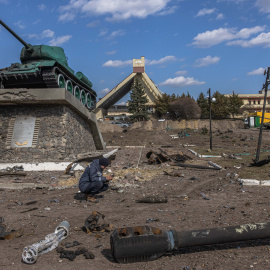 Un rescatista ucraniano examina un objeto explosivo junto a partes de vehículos militares rusos destruidos en el suelo frente a la estación de tren donde estaban estacionadas las fuerzas rusas, en la ciudad de Trostyanets, recapturada por e