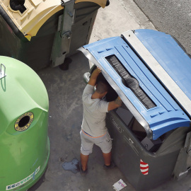 Fotografía de archivo de un hombre buscando en un contenedor de basura.