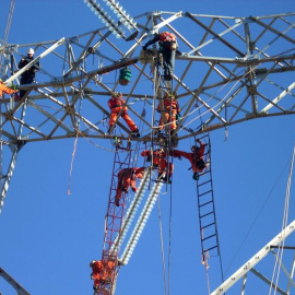 Empleados de Abengoa realizando trabajos de construcción en una torre de línea de transmisión en Chile.