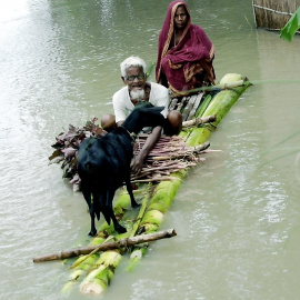 Una pareja bangladesí con una cabra navegan por las aguas de una gran inundación en el sur del país en busca de refugio AFP PHOTO/ Farjana K. GODHULY