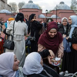 Una mujer ofrece dulces a otras mujeres musulmanas reunidas frente a la Mezquita Azul tras participar en las oraciones del Eid al-Fitr, en Estambul, a 21 de abril de 2023.