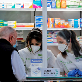 Dos empleadas de una farmacia atienden a un cliente.