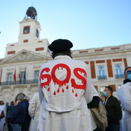 Un hombre con una bata donde se puede leer "SOS" en una concentración en defensa de la Atención Primaria, a 13 de noviembre de 2021, en Madrid