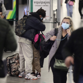 Dos personas, con maletas, se abrazan junto al control de equipajes, en el día en que arranca la operación salida de Semana Santa 2022, en la estación Madrid - Puerta de Atocha