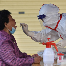 Un trabajador de la salud que usa un equipo de protección personal recolecta muestras de hisopos de un residente (18/4/21)