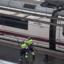 Dos trabajadores pasan junto a un tren AVE de Renfe en un andén en la estación de Atocha, en Madrid. E.P./Marta Fernández Jara