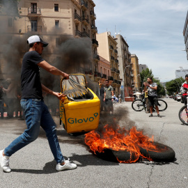 Un repartidor de Glovo quema una mochila durante una protesta tras la muerte de un compañero en Barcelona.-REUTERS/ALBERT GEA