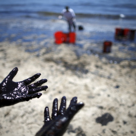 Varios voluntarios limpian una de las playas afectadas por el vertido. / LUCY NICHOLSON (REUTERS)