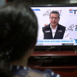 Un mujer escucha un discurso del magistrado presidente del Tribunal Supremo Electoral (TSE) David Matamoros, a través de un canal nacional de televisión en Tegucigalpa (Honduras). EFE/Gustavo Amador