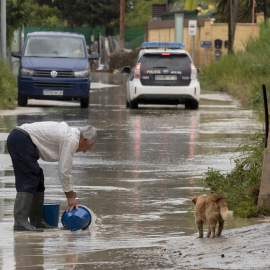 Un hombre retira agua de la calle con dos cubos, este viernes 26 de mayo de 2023, en el camino de la huerta de abajo en Molina de Segura.