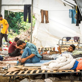 Refugiados del campo de acogida de Vucjak (Bosnia) descansan este jueves en el que fue un antiguo vertedero de basuras, situado en un bosque rodeado de campos de minas y sin agua corriente. EFE