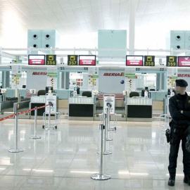 Un mosso de esquadra ante los mostradores de facturación de Iberia, en el aeropuerto de Barcelona-El Prat. EFE/Andreu Dalmau/Archivo