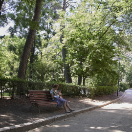 Una señora sentada en un baco del parque Quinta de los Molinos, a 24 de julio de 2022, en el distrito de San Blas-Canillejas, Madrid (España)