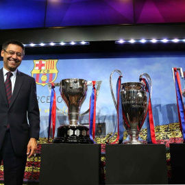 El presidente del FC Barcelona, Josep María Bartomeu, posa con los trofeos de la Liga, Liga de Campeones y Copa del Rey al finalizar su comparecencia. /EFE