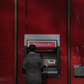 Una mujer utiliza un cajero automático en una oficina del Banco Santander en el centro de Londres. AFP/Carl Court