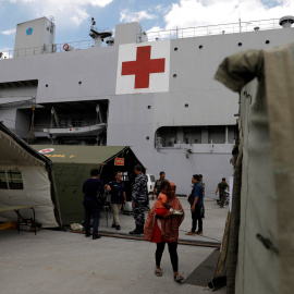 Una mujer sostiene a su hijo mientras espera tratamiento en el barco del hospital de la Armada de Indonesia. REUTERS