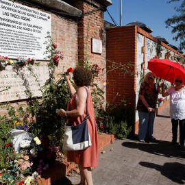 Una mujer coloca una rosa en el muro dedicado a las 13 jóvenes republicanas en el homenaje convocado por el PCE. / EFE