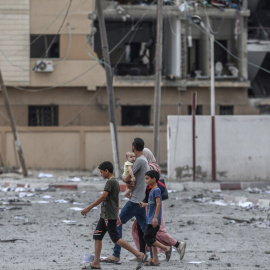 Una familia palestina camina frente a edificios destruidos por los ataques aéreos en la ciudad de Gaza