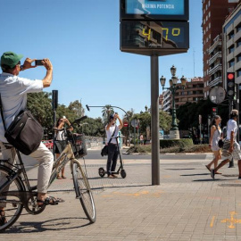 Varias personas fotografían un termómetro que marca 47 grados, este viernes en Valencia. EFE/Biel Aliño