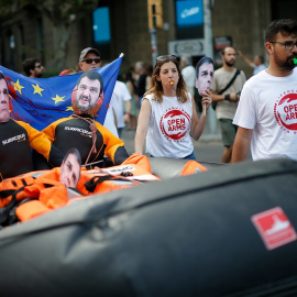 13/07/2019 - Manifestantes sostienen un bote hinchable con imágenes de las caras del presidente Pedro Sánchez y el ministro del Interior italiano, Matteo Salvini, en una protesta en Barcelona. / AFP - PAU BARRENA